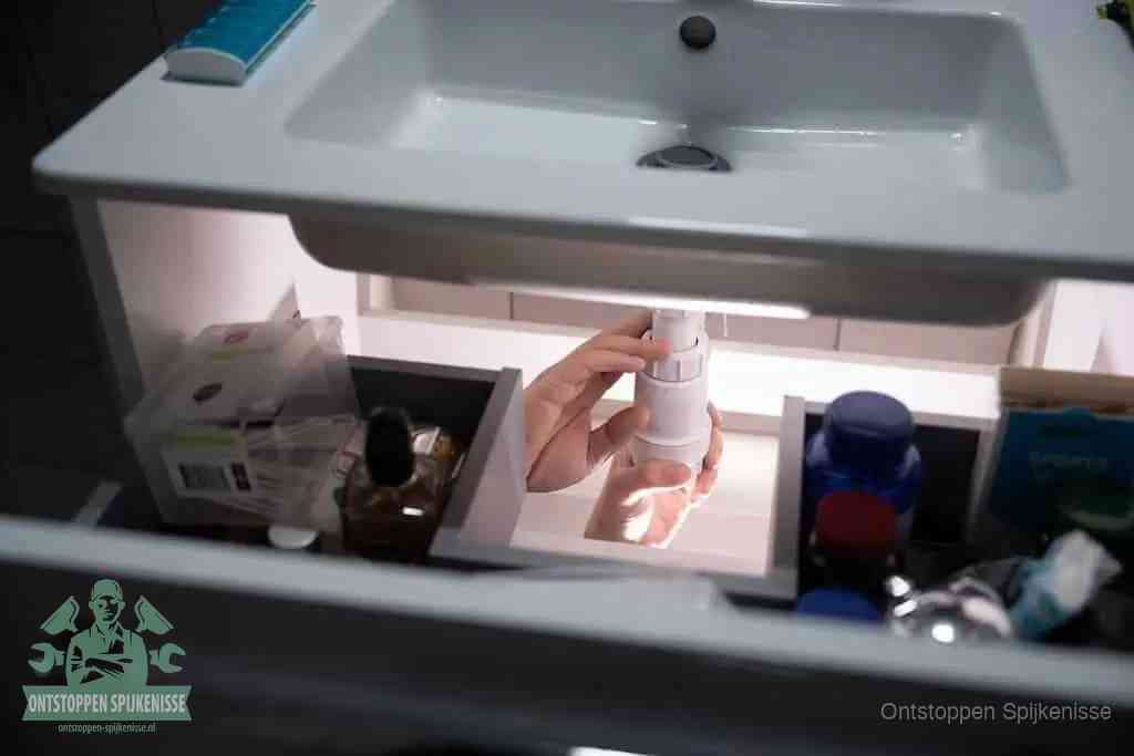 Een pompfles met zeep boven een wastafel, de heet water en afwasmiddel-methode om een vetprop in de afvoer los te maken in Spijkenisse