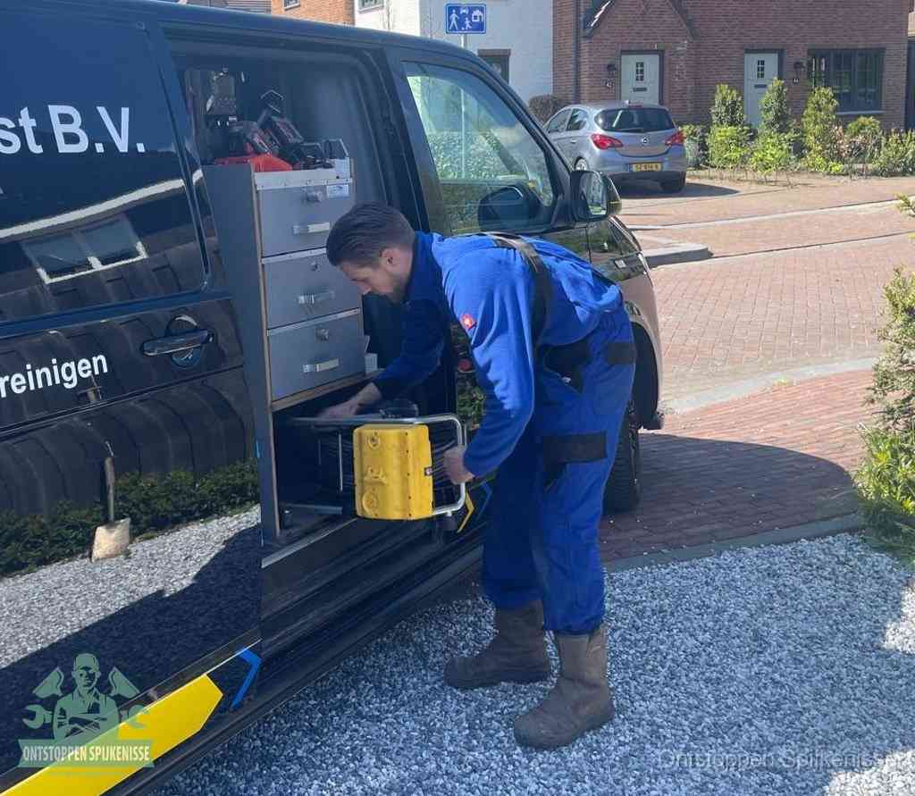 Een monteur pakt buiten op de oprit gereedschap uit de bedrijfsbus, het moment om een professional in te schakelen voor een verstopte afvoer in Spijkenisse