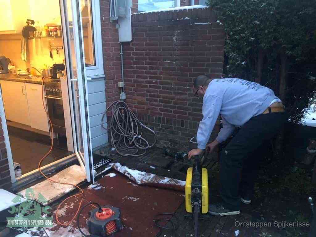 Een monteur werkt buiten bij een open riool-/grondput met een elektrische ontstoppingsmachine om een verborgen afvoerprobleem op te sporen in Spijkenisse