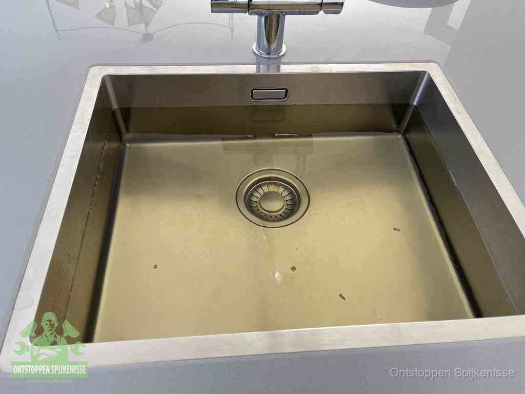 Stilstaand water in een rvs spoelbak dat niet wegloopt, een duidelijk signaal van een gootsteenverstopping in Spijkenisse