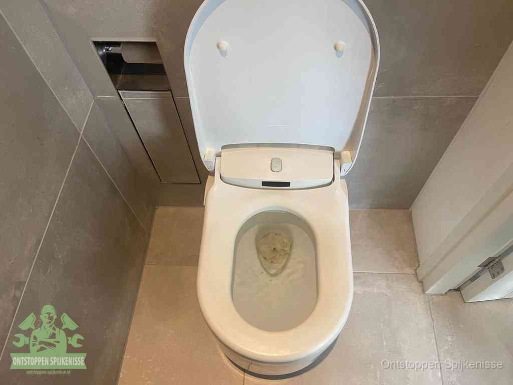 Een wit hangtoilet waarin een prop wc-papier op het water blijft drijven, een duidelijk signaal van een verstopte wc in Spijkenisse