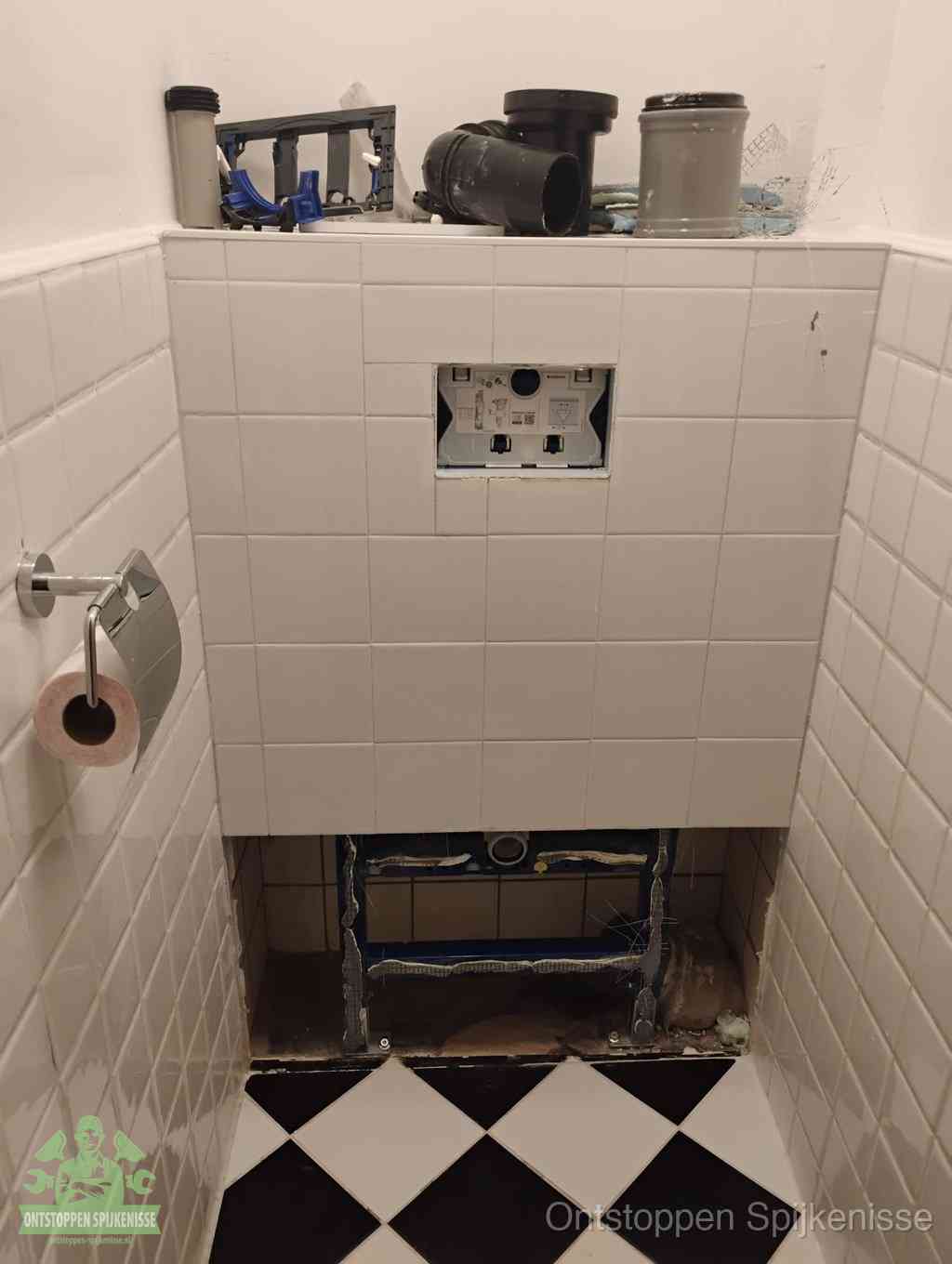 Een toiletruimte waar het hangtoilet en de inbouwreservoir-onderdelen zijn vrijgelegd voor onderhoud, periodiek nazicht voorkomt een wc-verstopping in Spijkenisse